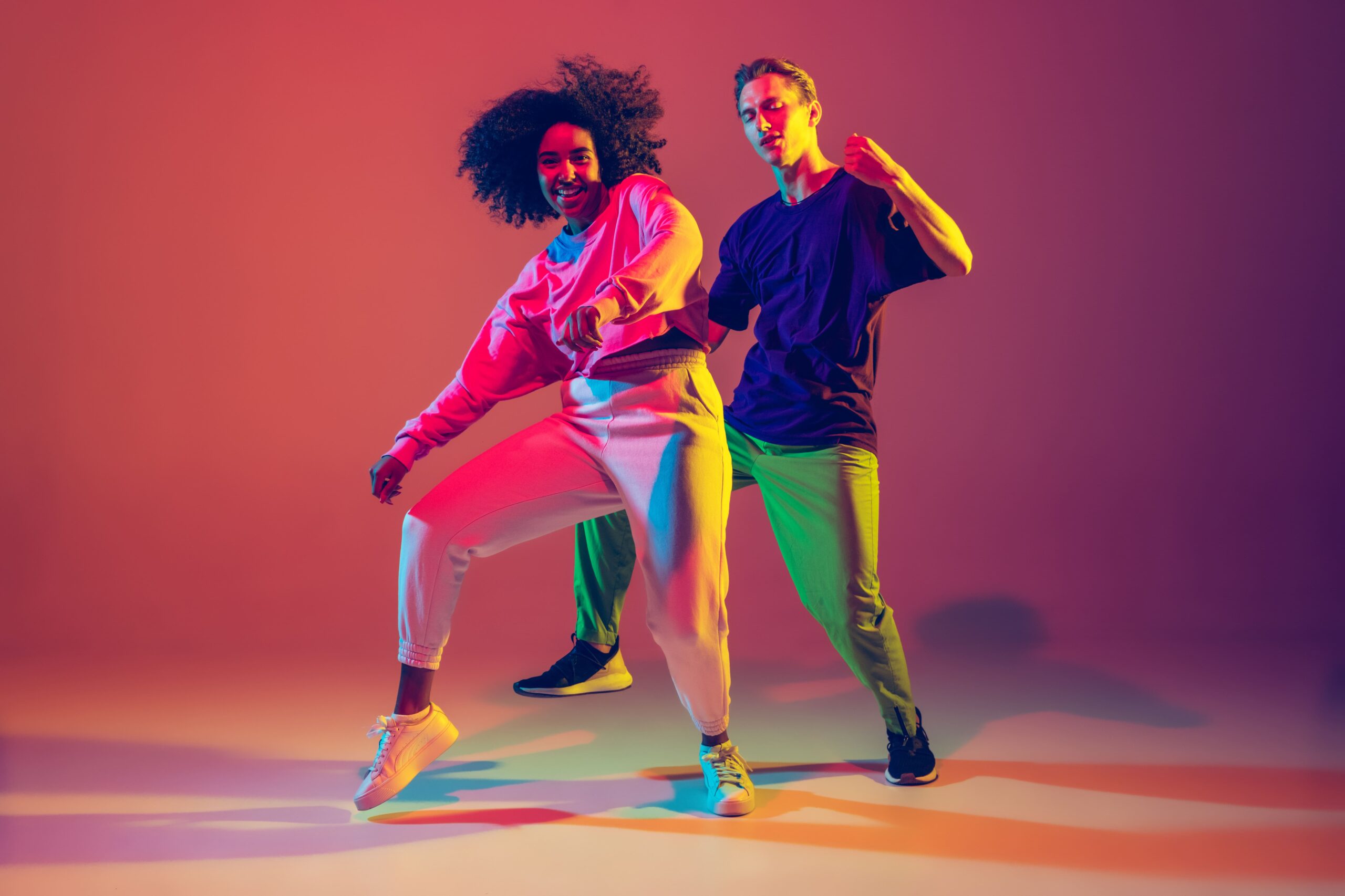 dance-time-stylish-men-and-woman-dancing-hip-hop-in-bright-clothes-on-green-background-at-dance-hall-in-neon-light-min (1)